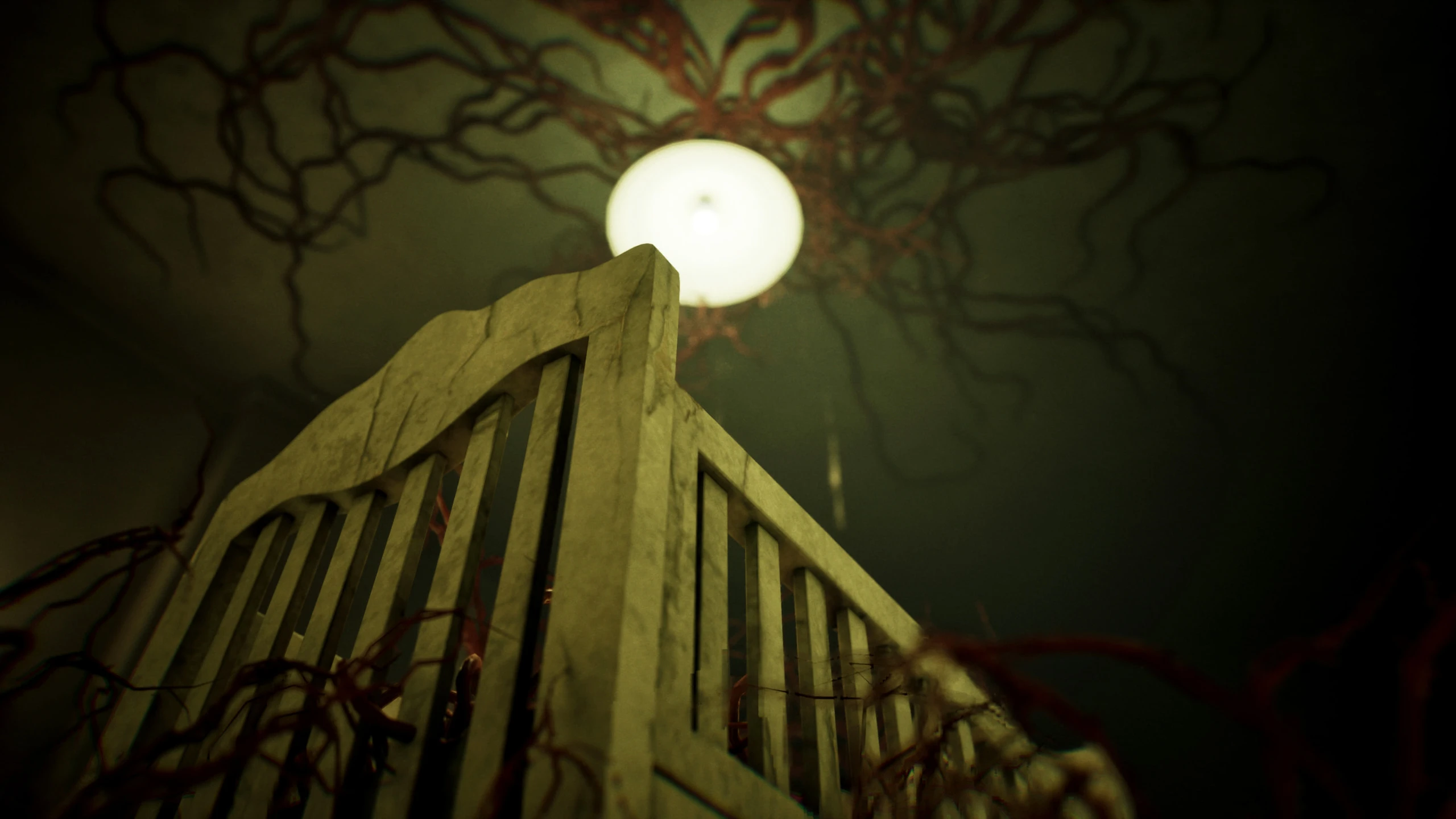 Looking up past the rail of a white wooden cot at a round ceiling light, with dark red tendrils spreading across the ceiling around it