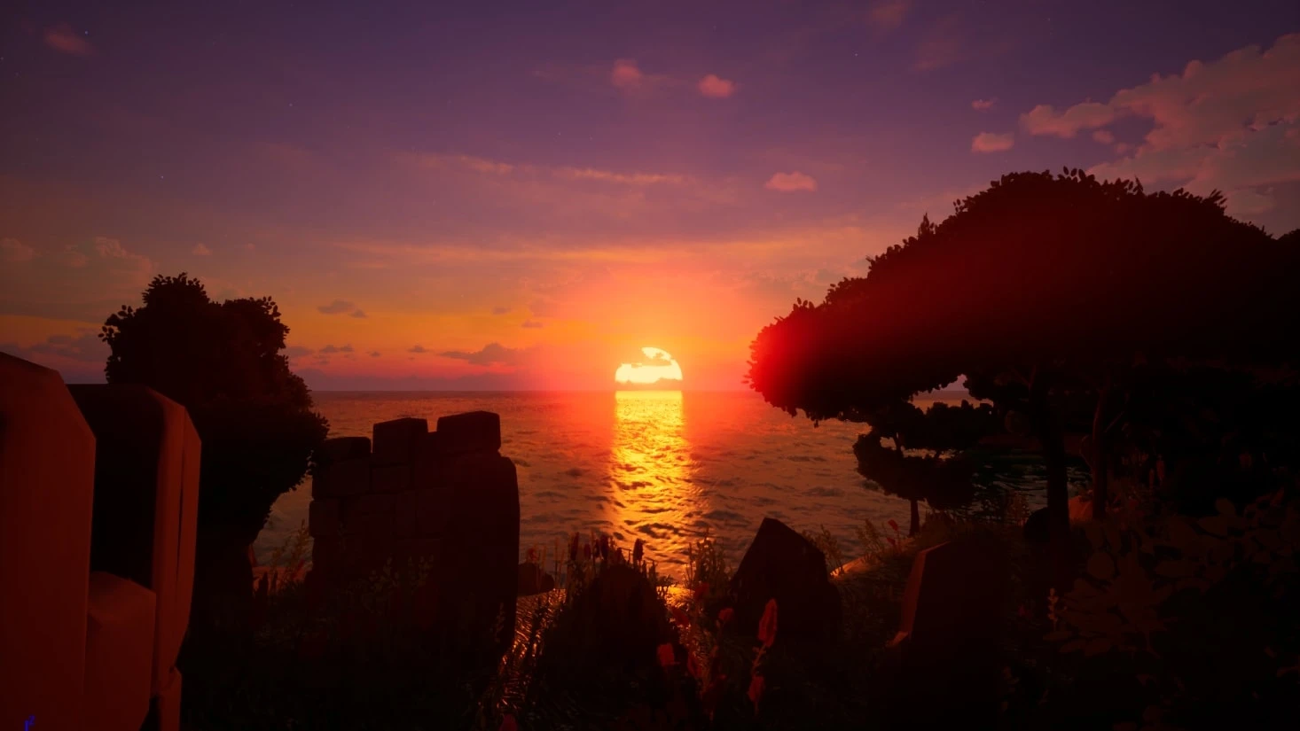 A sunset over open sea framed by silhouetted trees and a ruined wall, the sun's reflection breaking up across the wave surface